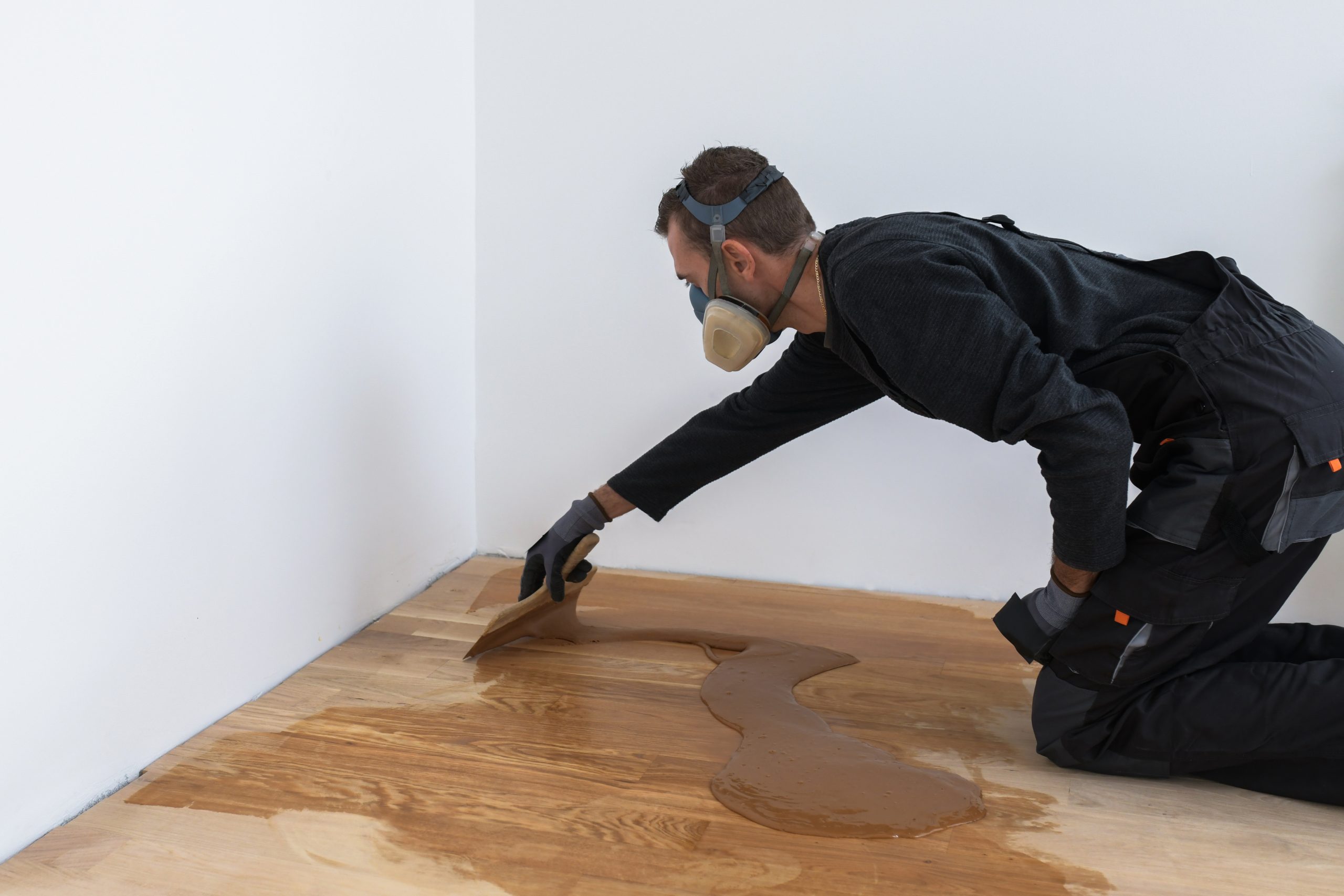 Wood Floor Staining in Carshalton – technician trowel-applying stain across a sanded oak plank hardwood floor for an even, deep tone.