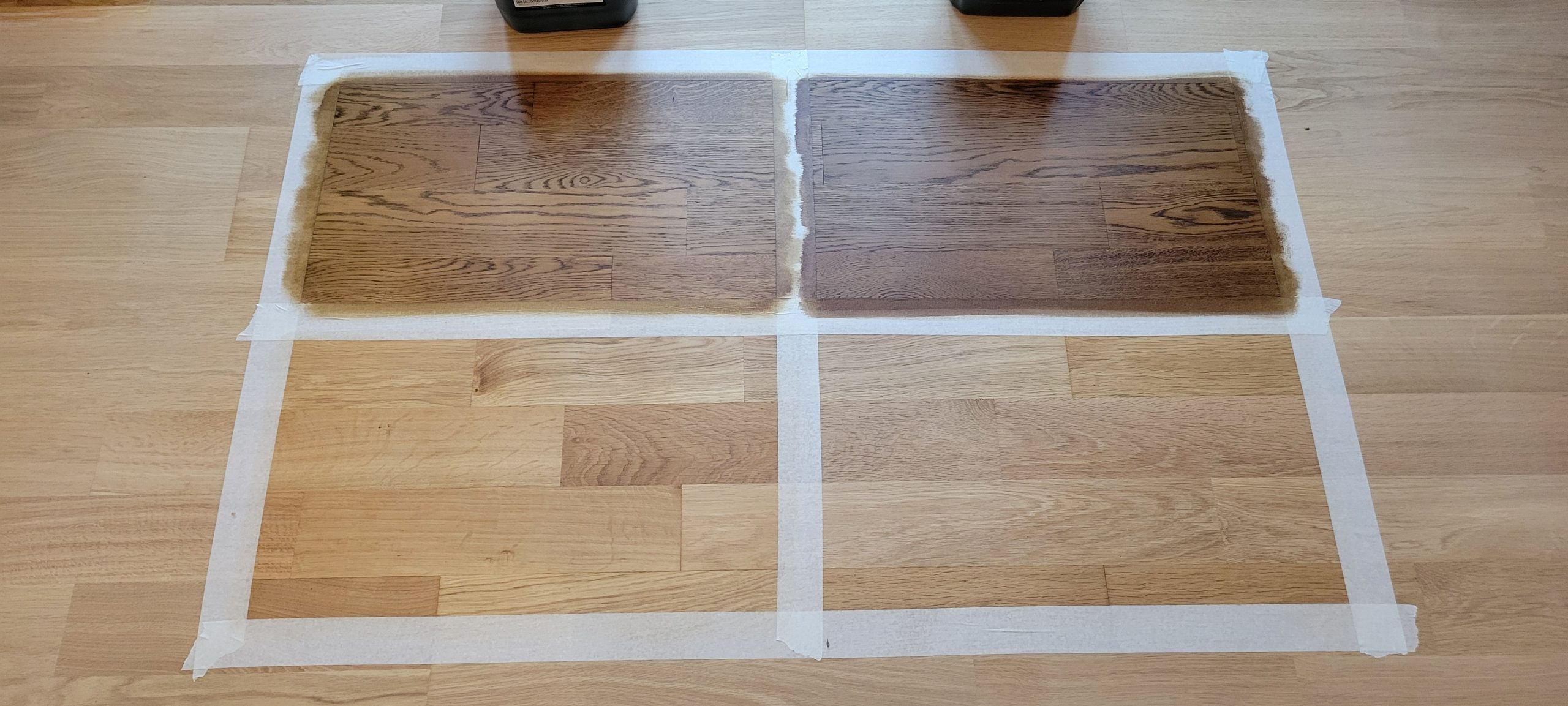 Wood Floor Staining in Carshalton – taped sample squares on an oak solid hardwood floor showing mid- and dark-brown test patches for tone selection.