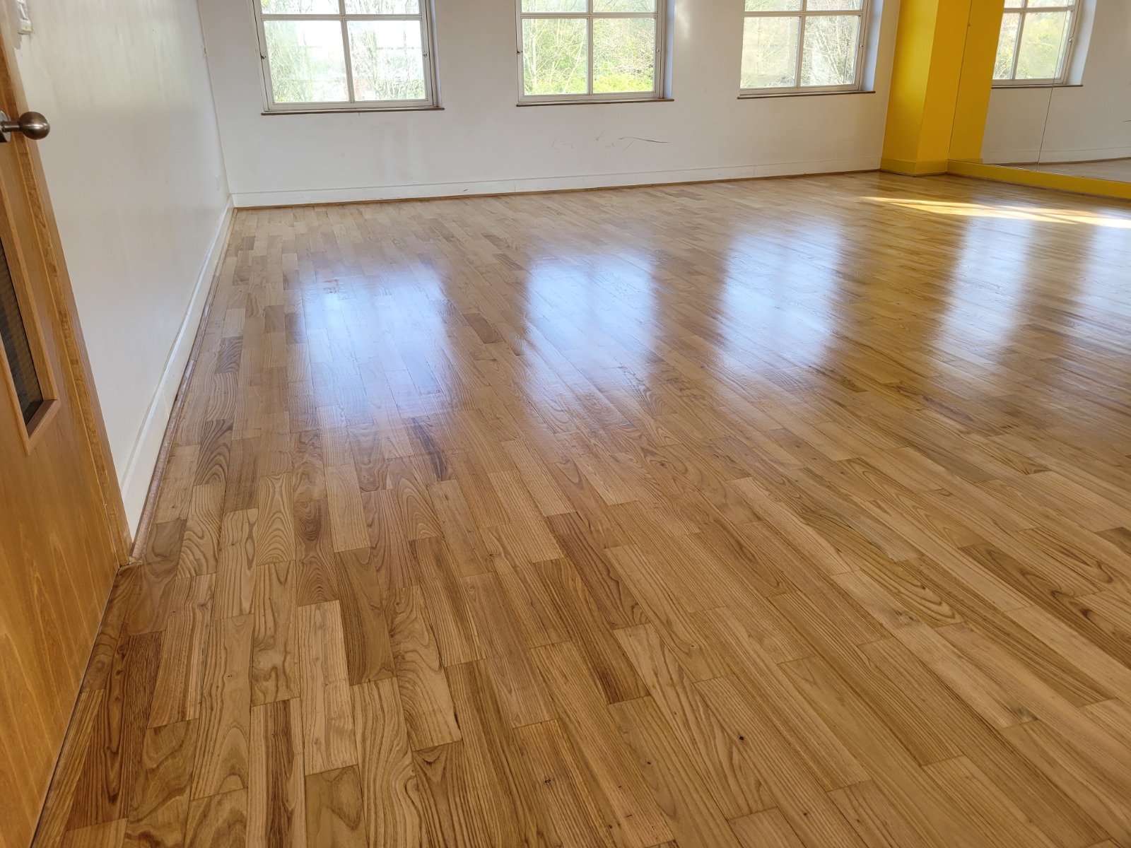 Wood Floor Staining in Carshalton – freshly stained and sealed oak strip hardwood floor in a bright studio, showing a smooth satin sheen.