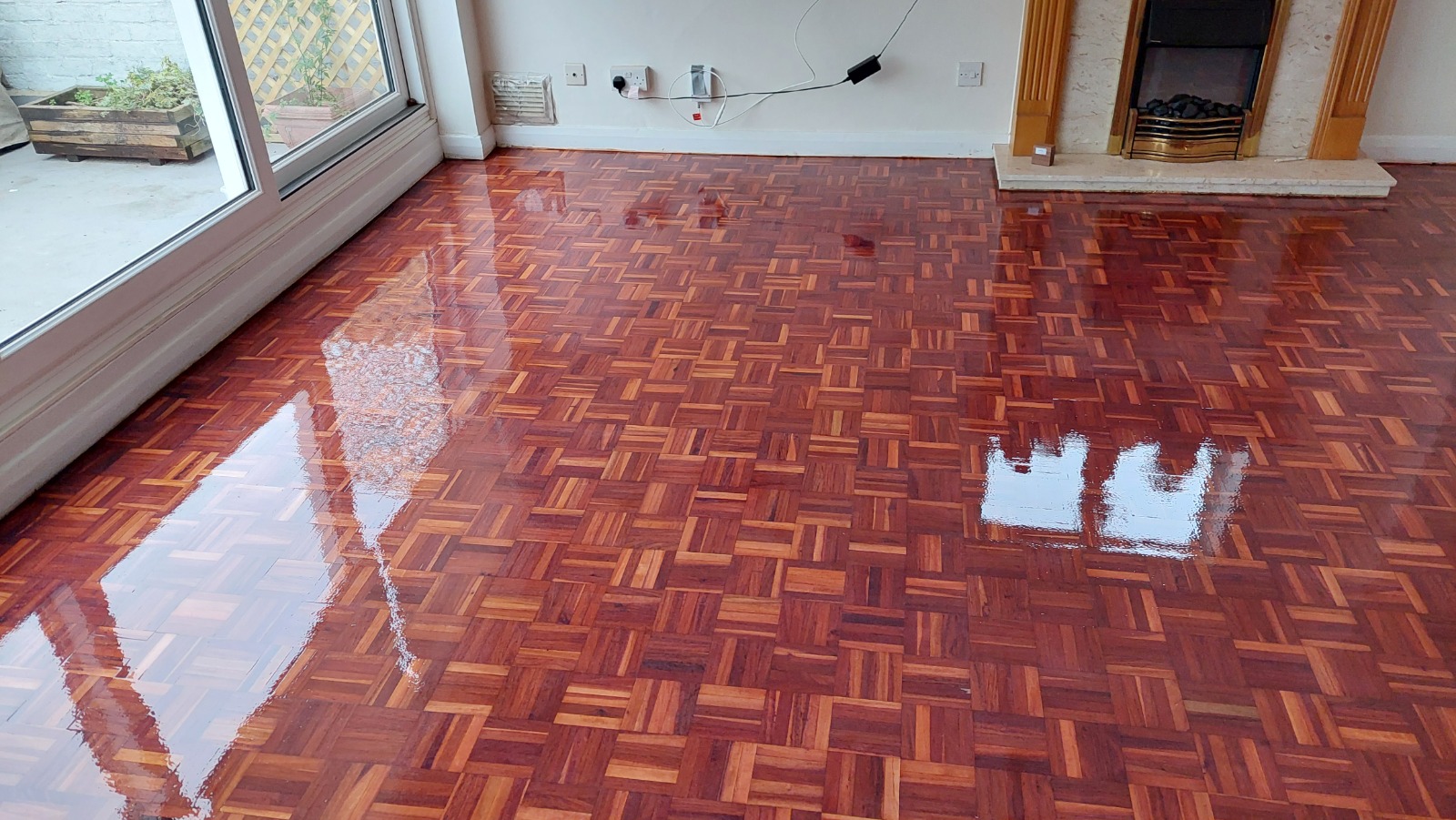 High-gloss finish on a reddish-brown basketweave parquet floor in a living room after expert wood floor sanding in Carshalton.