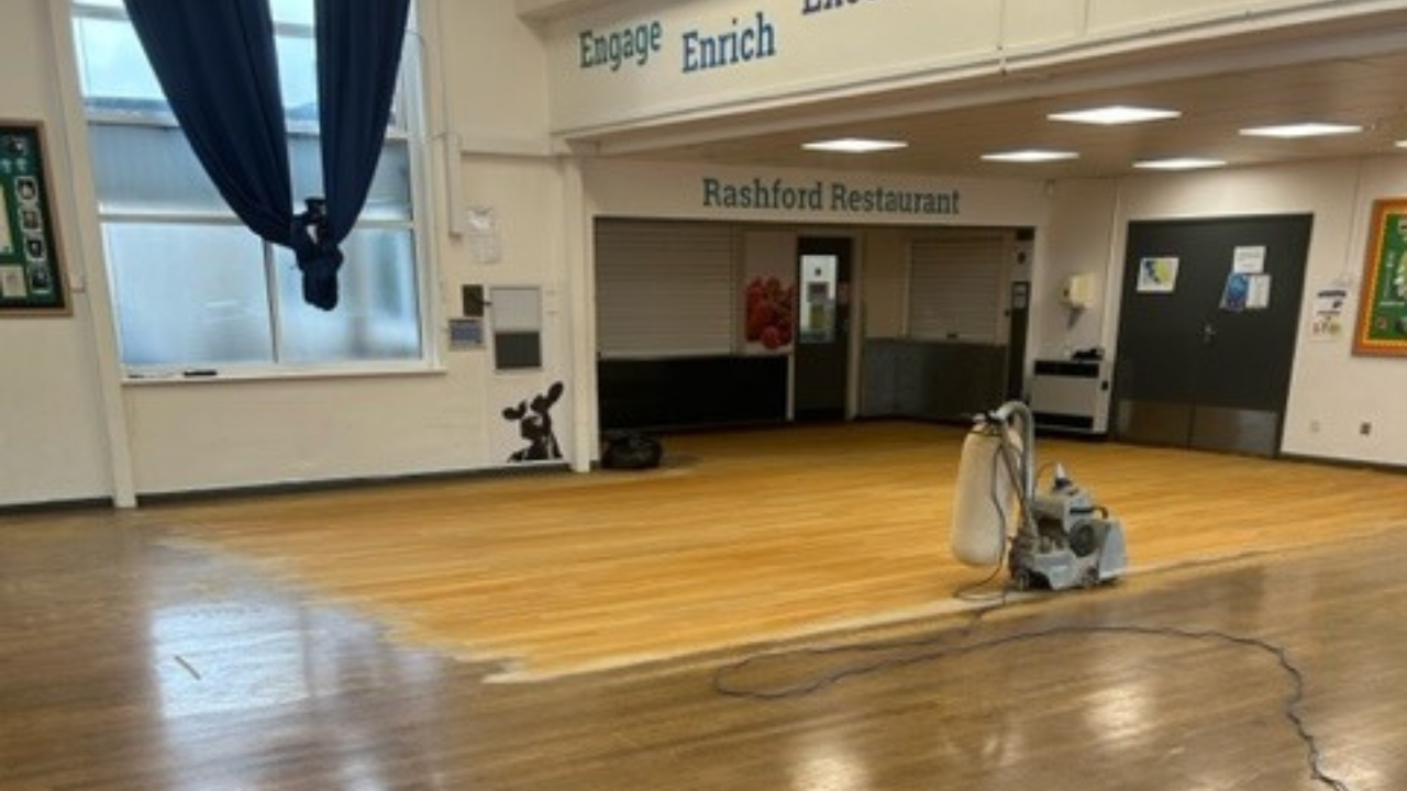 Commercial Floor Sanding in Carshalton on an oak hardwood school restaurant floor, midway through sanding from dark, worn boards to fresh timber.